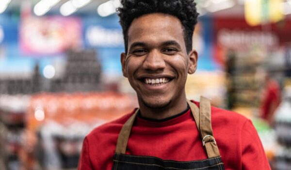 African American teenager smiling at his workplace in a retail store.